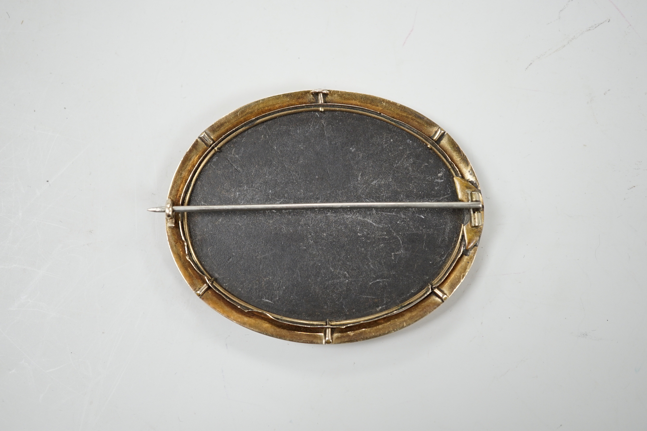 A Victorian yellow metal mounted pietra dura set oval brooch, depicting a bird and butterfly, 63mm.